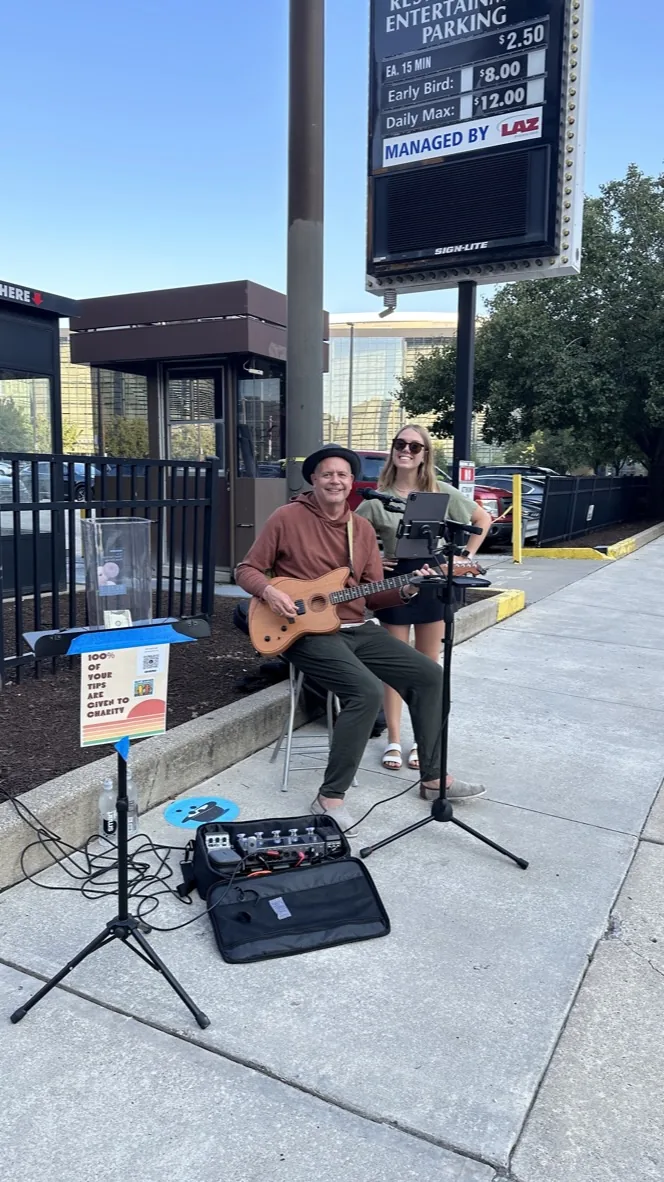 Mike Bush performing beside Charity Challenge voting buckets
